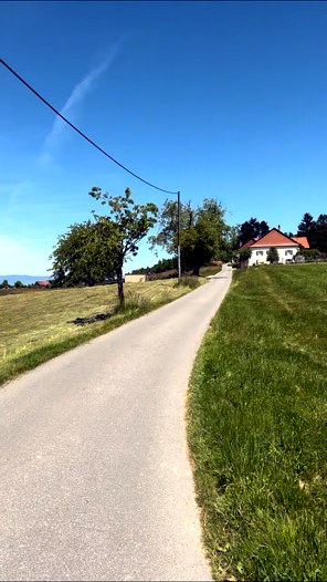 Petite route de campagne bordée de verdure en direction d'une ferme